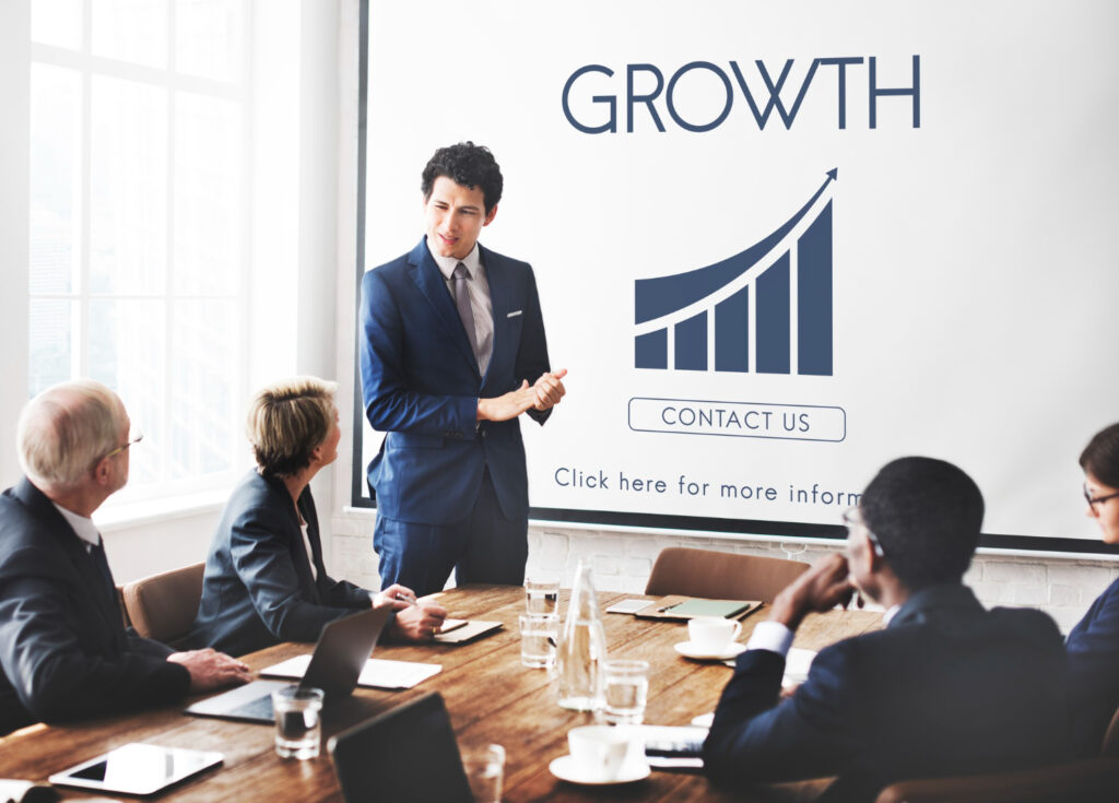 A business executive presenting business growth strategies and AI performance metrics to a team in a boardroom meeting