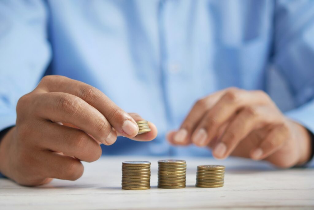 Close-up of a person stacking gold coins on a table, symbolizing return on investment and financial growth through SEO services.